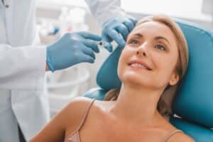 A woman smiling while getting a BOTOX® Cosmetic injection in Temecula, CA